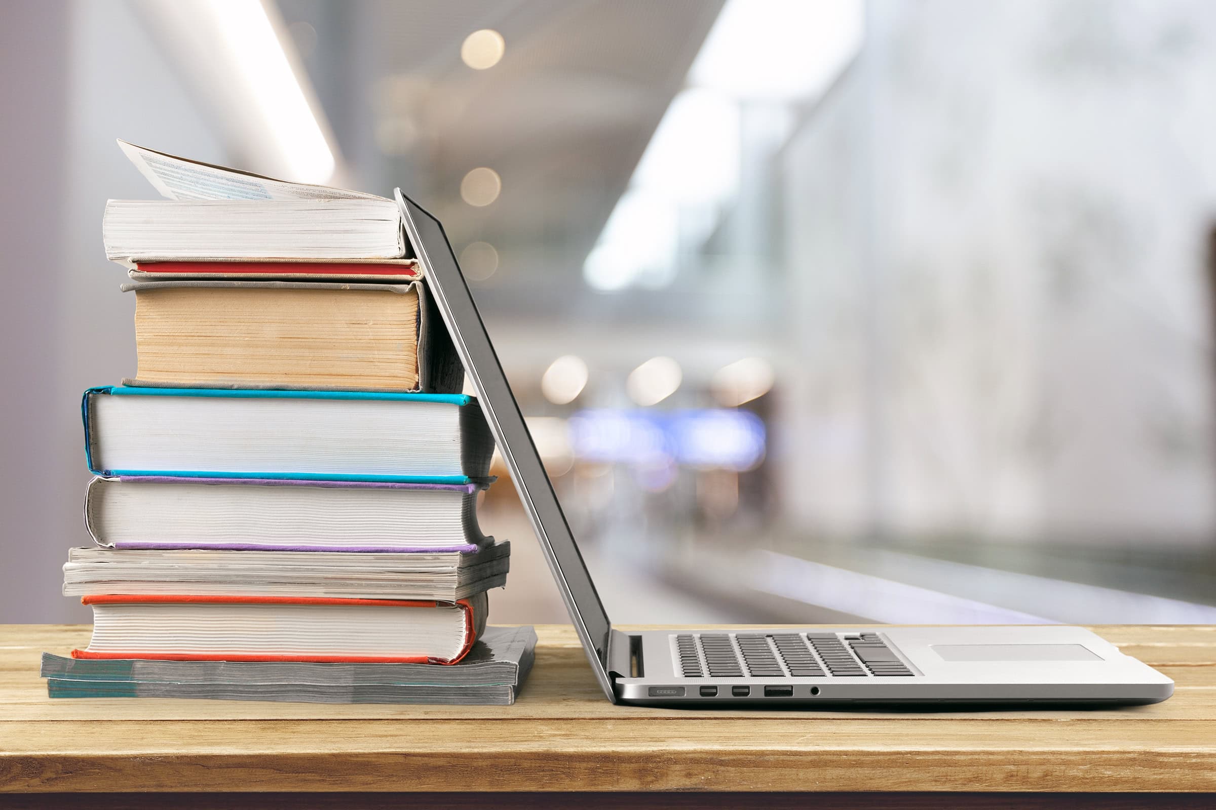 stack-of-books-with-laptop Stack of books with laptop on wooden table