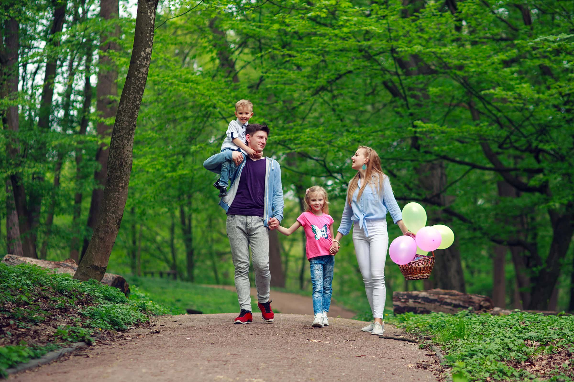 Family father and mother with two children a son and daughter walking in the summer green city park on a picnic, happy holidays parents and children on nature