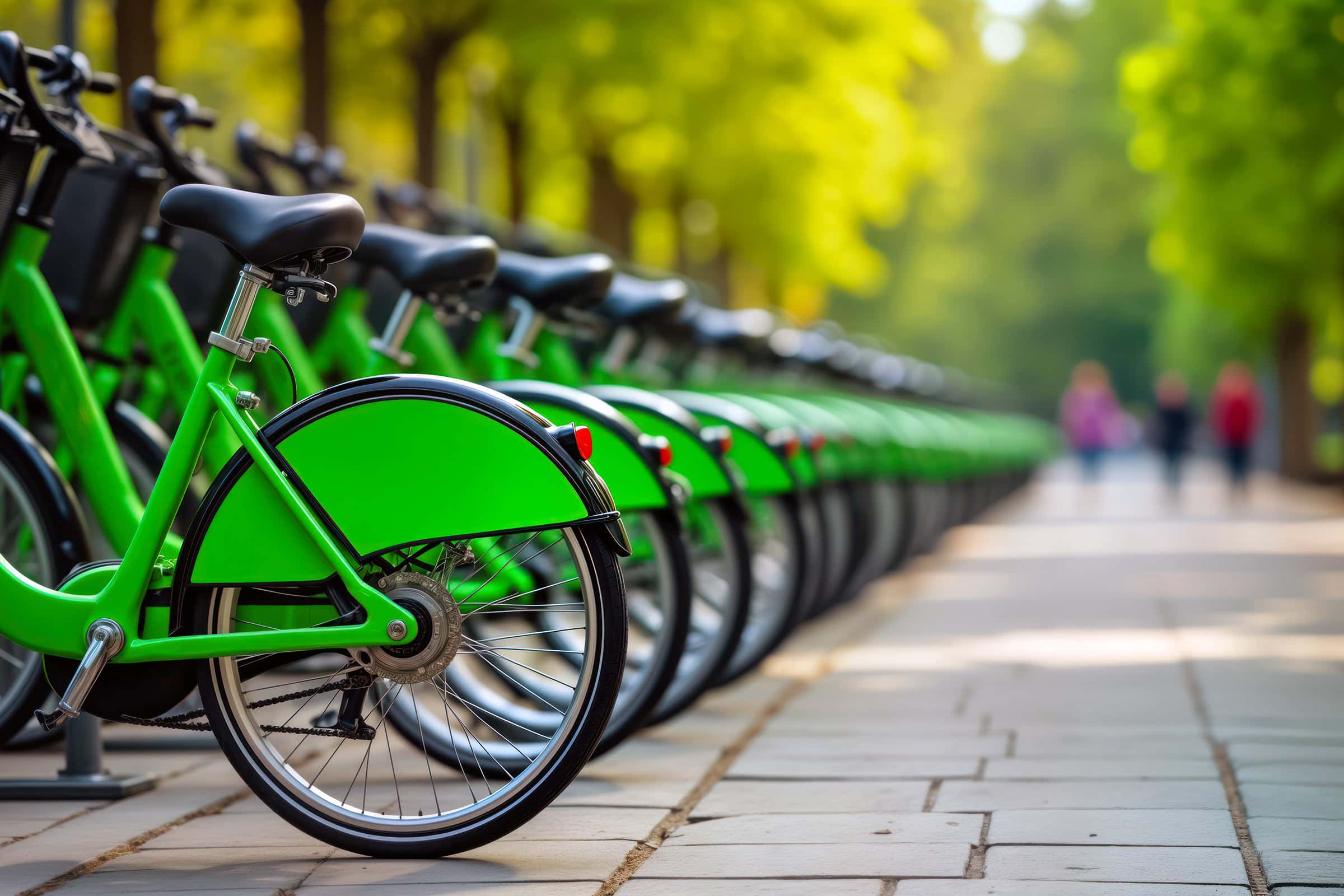 Park bike station with many bright, green bikes ready for rent. Eco-friendly public transport option. People walk by. Healthy lifestyle choice. Urban environment. Summer day. City park setting.