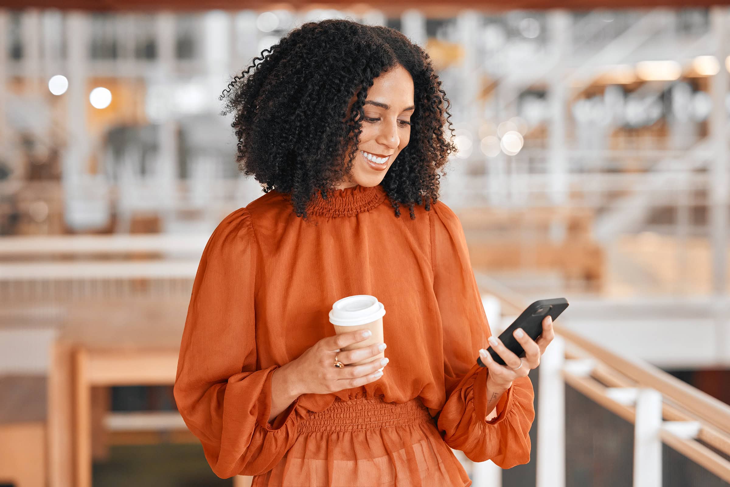 woman-reading-notification-on-phone Reading notification, coffee and woman with a phone at work for social media, email check or internet. Smile, break and young corporate employee on a mobile app and a drink in an office for business.