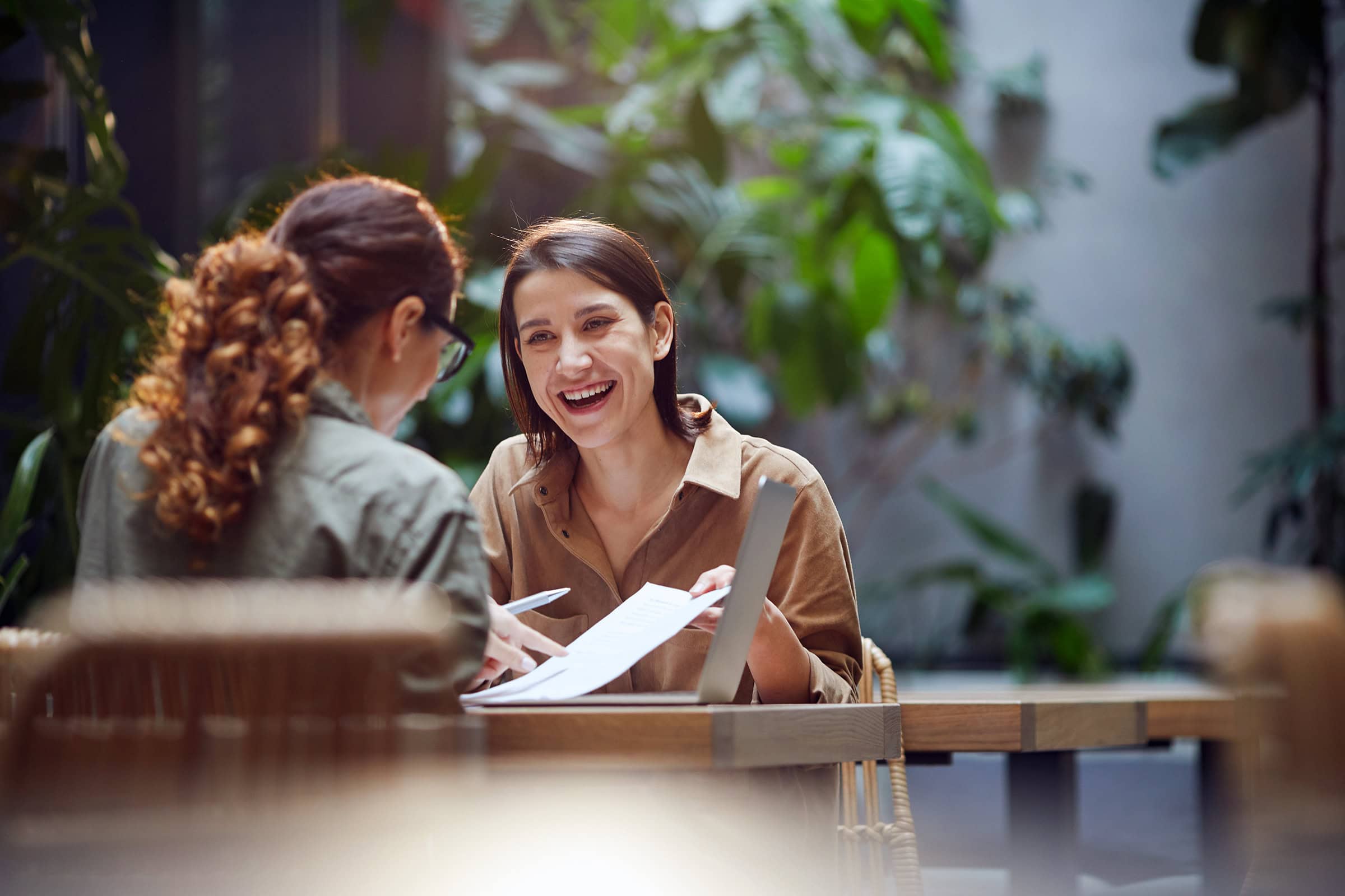 Portrait of cheerful young woman talking to friend or colleague outdoor.