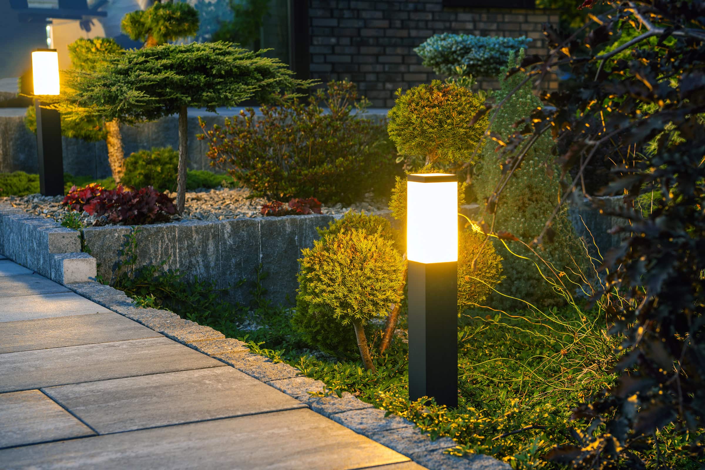 bollard-lamp-pathway-night Closeup of Glowing Bollard Lamp in Residential Backyard Garden.