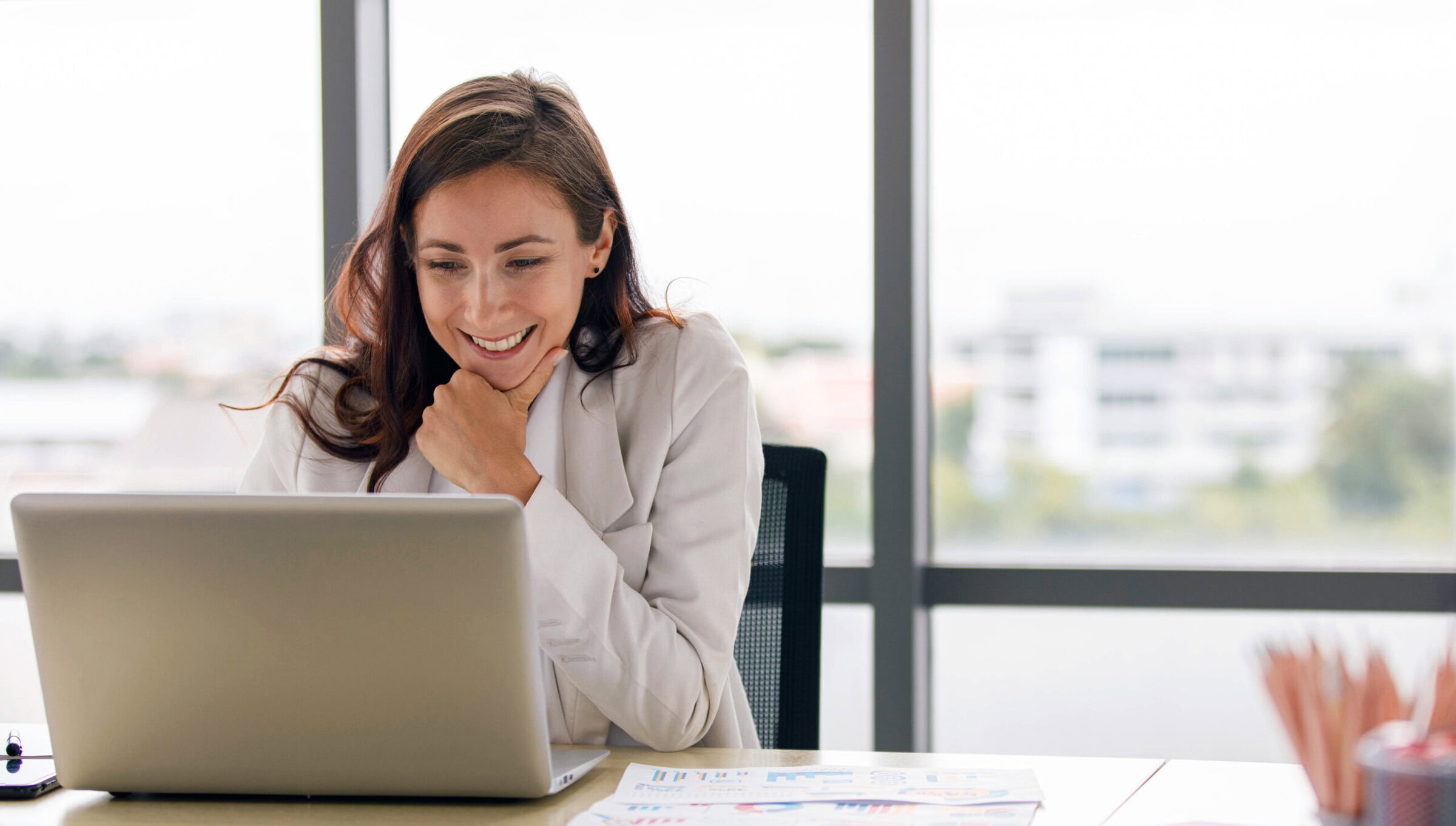 Happy female employee watching webinar on a laptop