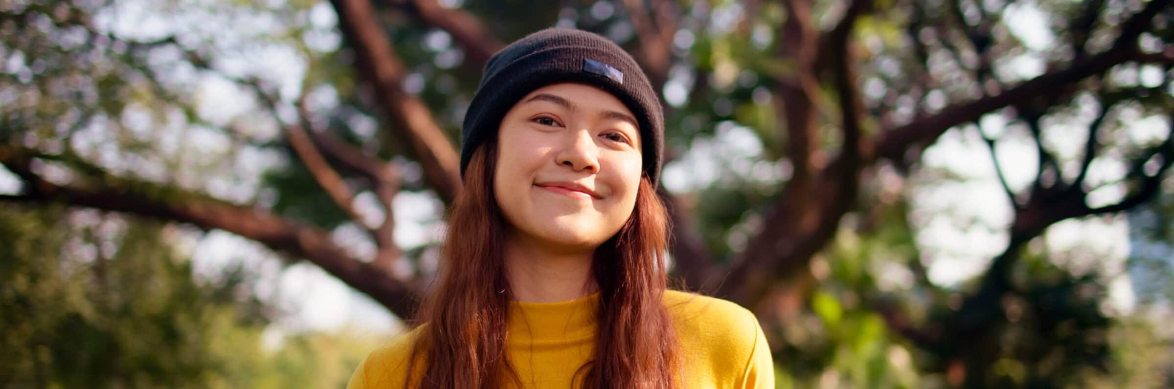Young person in a park by a tree in sunlight
