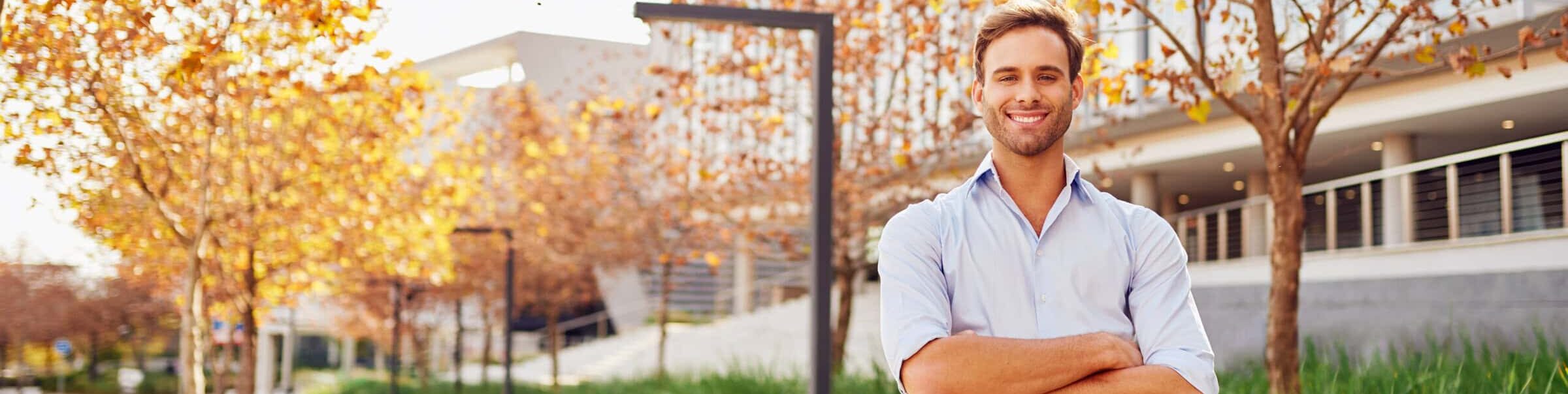 Young businessman smiling outside office with landscaping