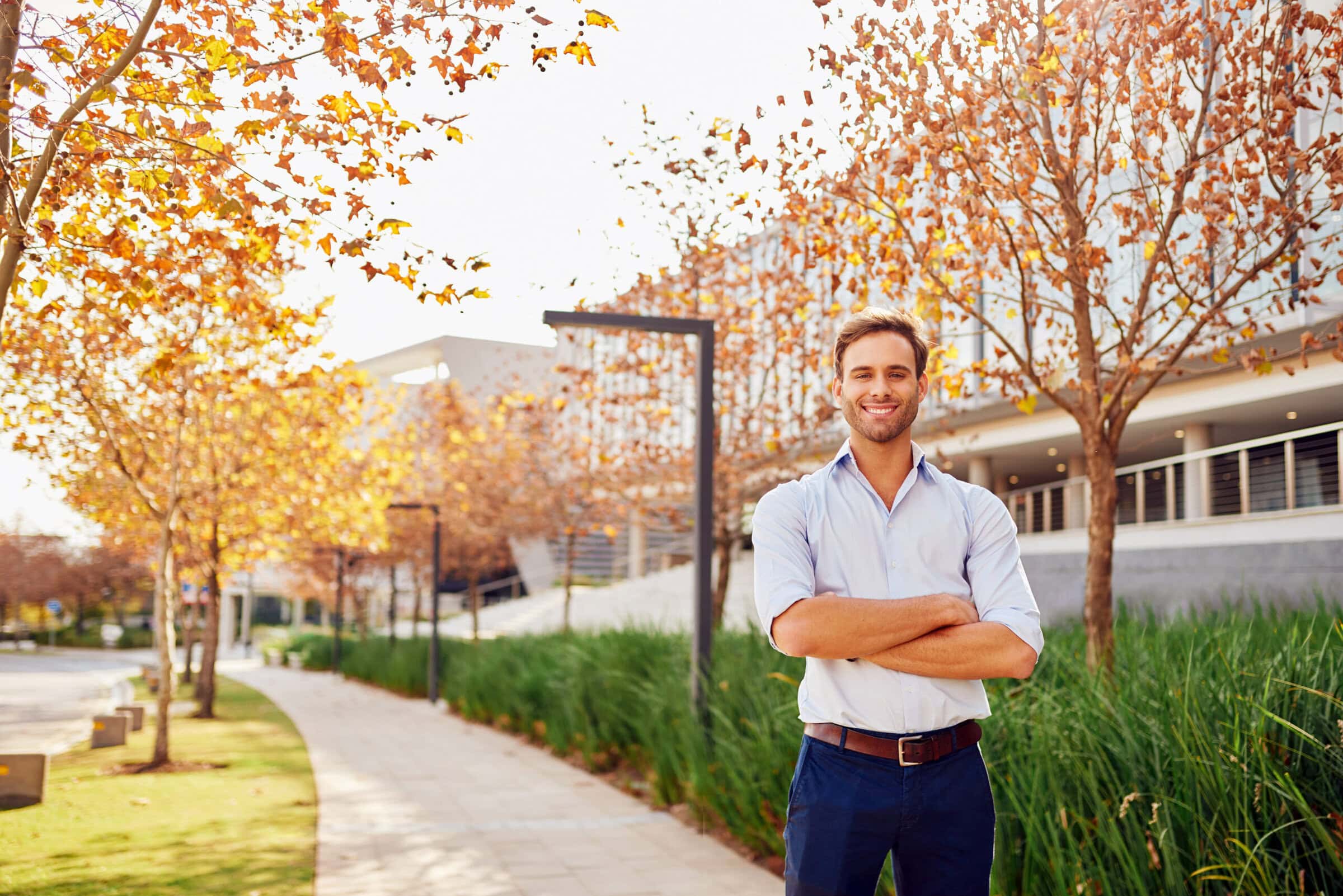 Young businessman smiling outside office with landscaping