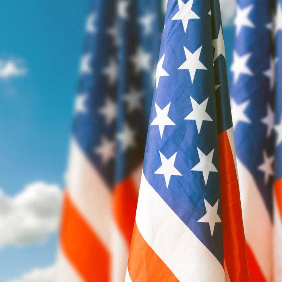 Large flag of usa waving in the wind against the sky with clouds on sunny day