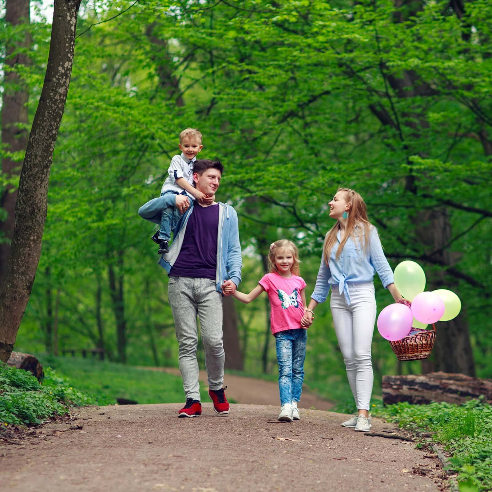 Family father and mother with two children a son and daughter walking in the summer green city park on a picnic, happy holidays parents and children on nature